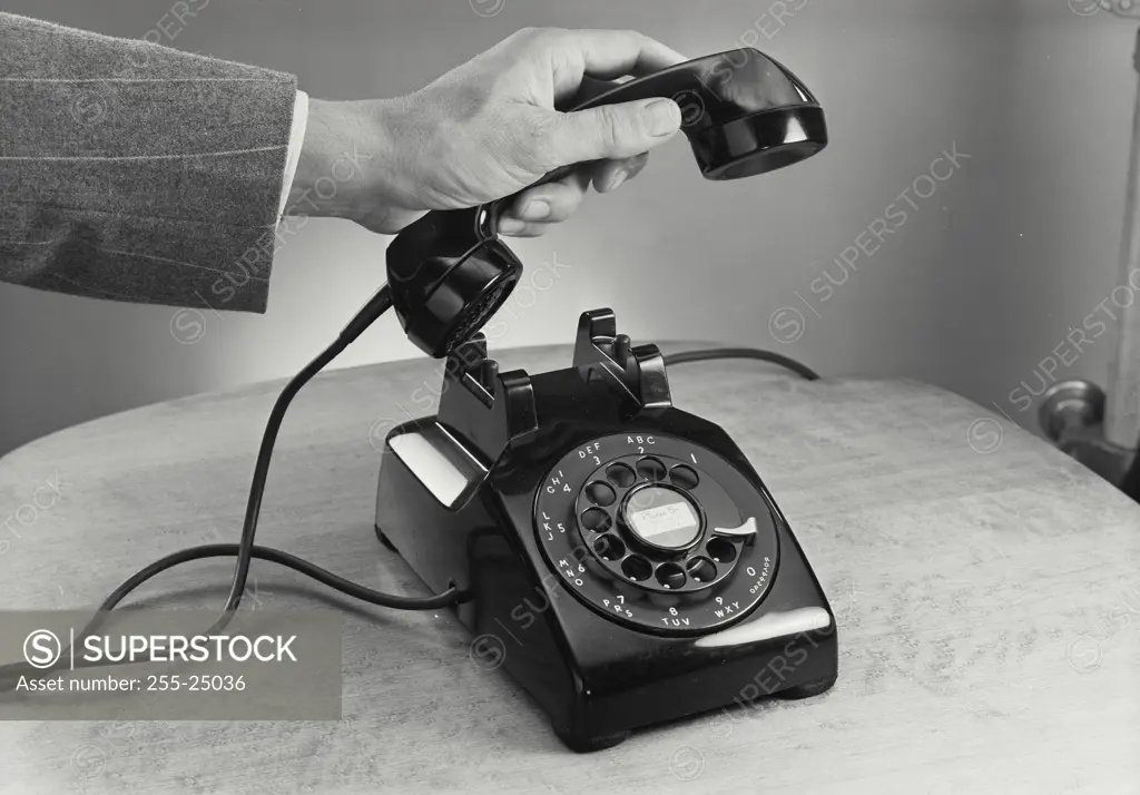 Vintage Photograph. Male hand picking up receiver of rotary telephone on wooden surface, Frame 6