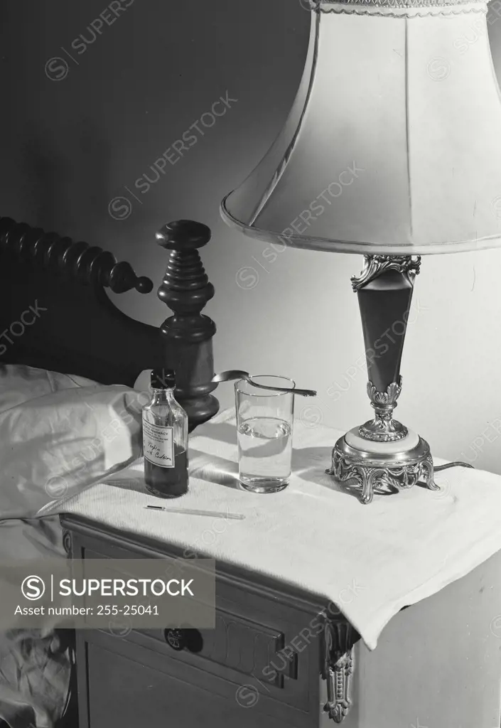 Vintage Photograph. Medicine placed on nightstand under lamp on a side table