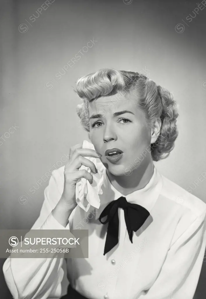 Vintage photograph. Woman in button shirt and western bowtie wiping face with handkerchief