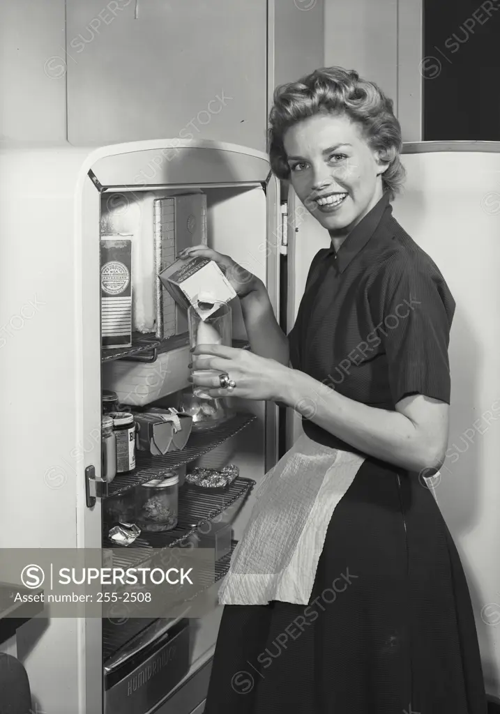 Vintage Photograph. Woman in apron looking in refrigerator. Frame 2