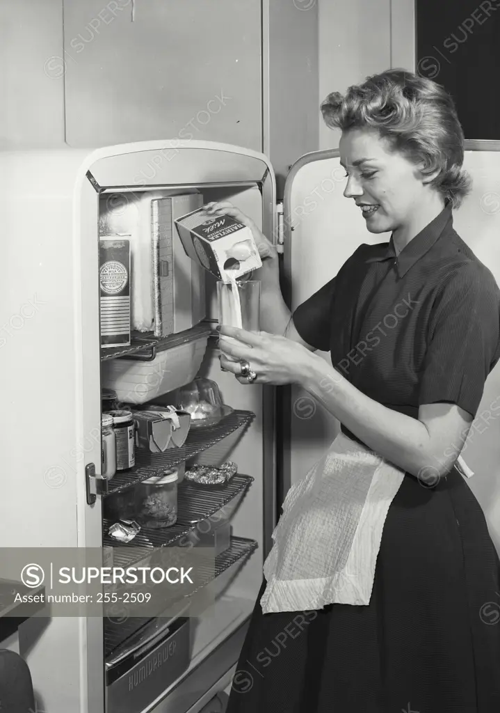 Vintage Photograph. Woman in apron looking in refrigerator. Frame 3