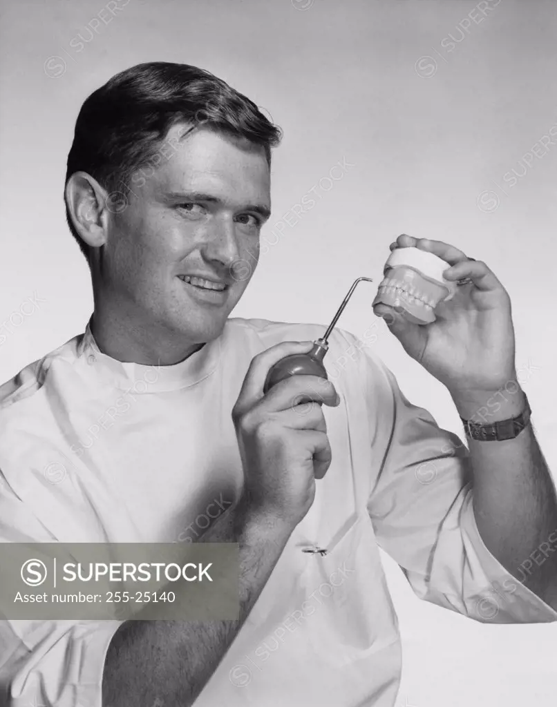 Portrait of mid adult man holding a set of dentures