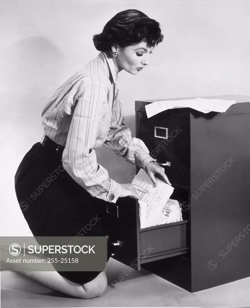 Side profile of a businesswoman searching documents in a filing cabinet