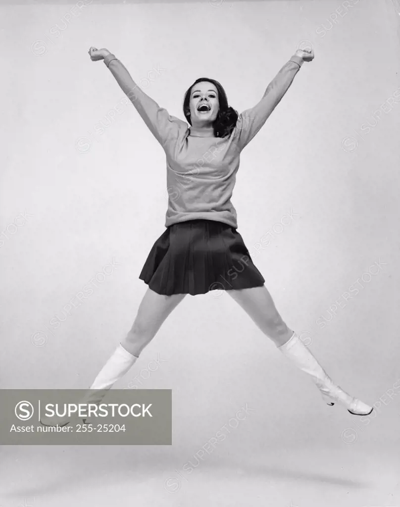 Portrait of a young woman jumping with her arms raised