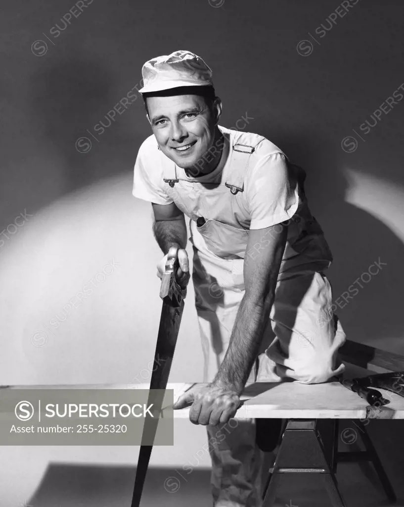 Portrait of a carpenter sawing a wooden plank