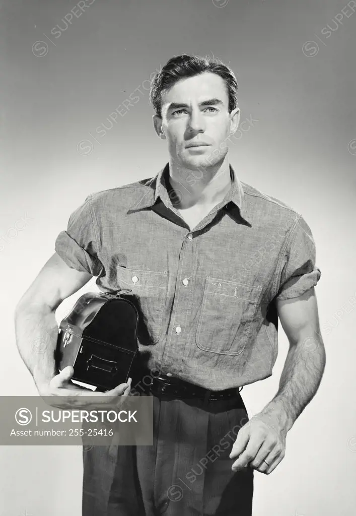 Portrait of man in button shirt holding lunch box.