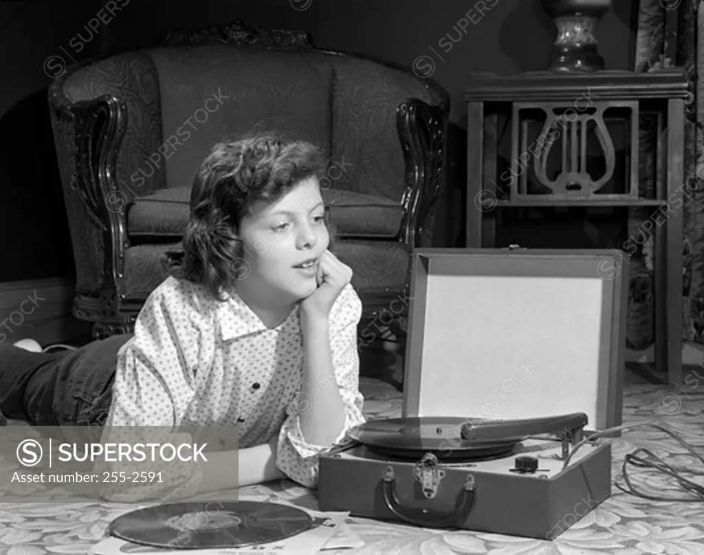 Girl listening to record player on floor in home