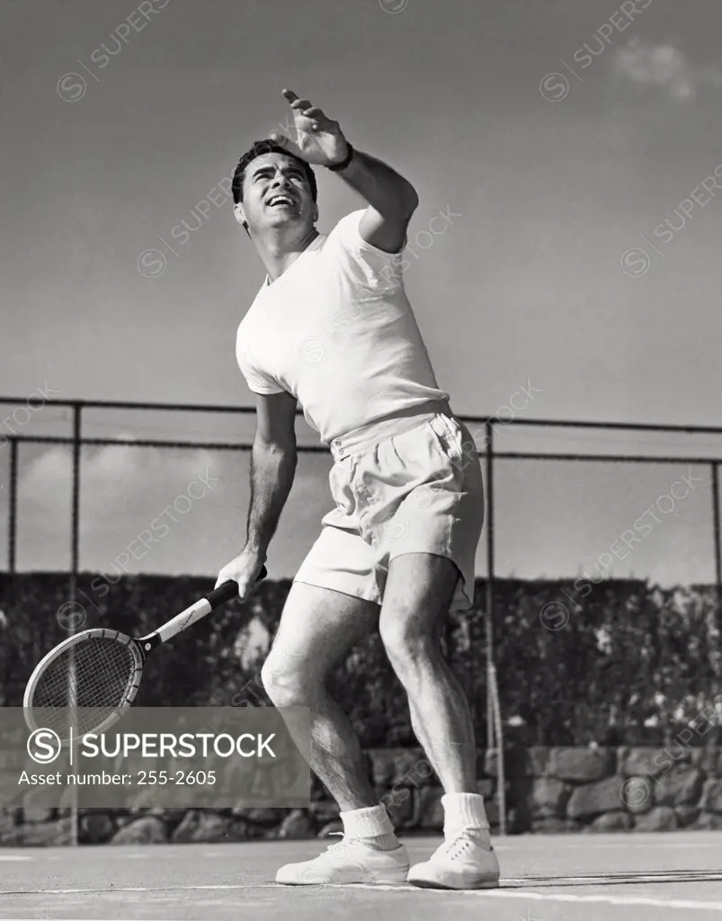 Low angle view of a young man playing tennis on a court
