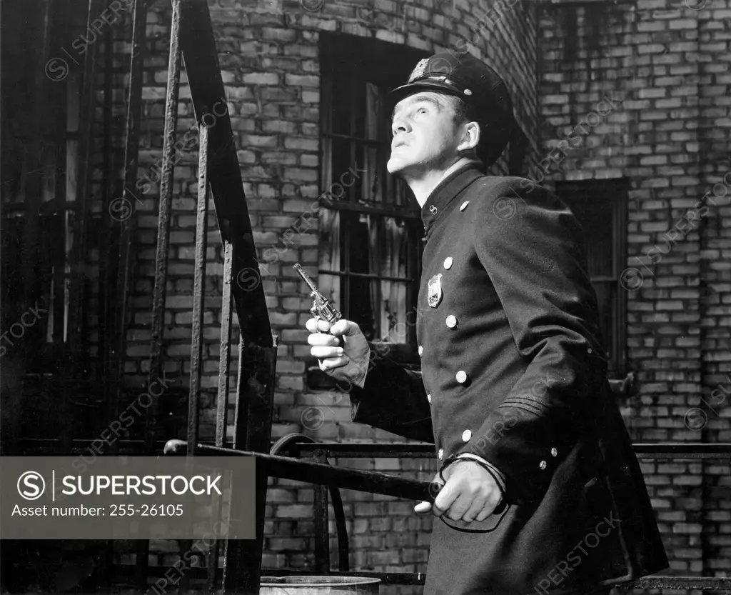 Side profile of a policeman holding a gun and a stick near a staircase