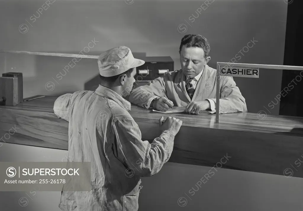 Vintage Photograph. Man in coat and hat standing at counter waiting for cashier