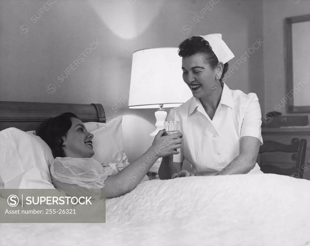 Female nurse giving a glass of water to a young woman