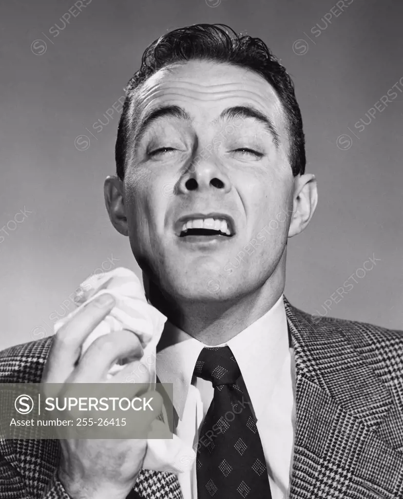 Vintage Photograph. Portrait of man sneezing into handkerchief