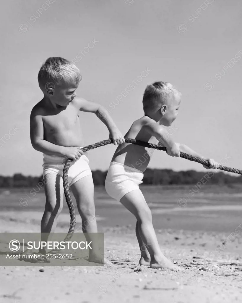 Two boys pulling a rope on the beach