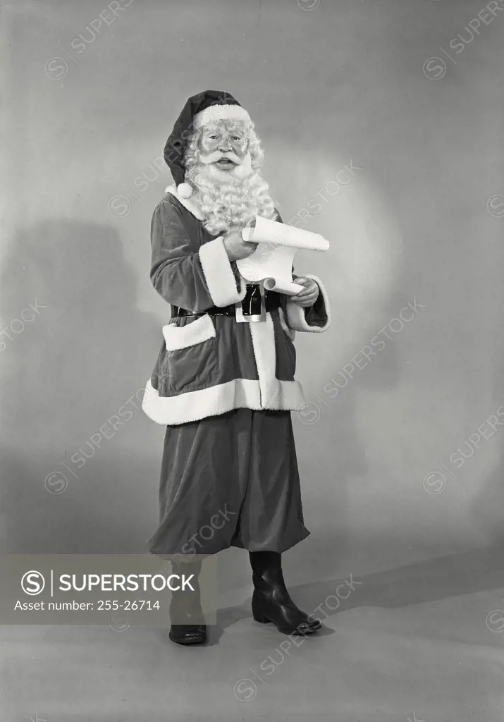 Vintage photograph. Man in Santa Claus costume holding list of names