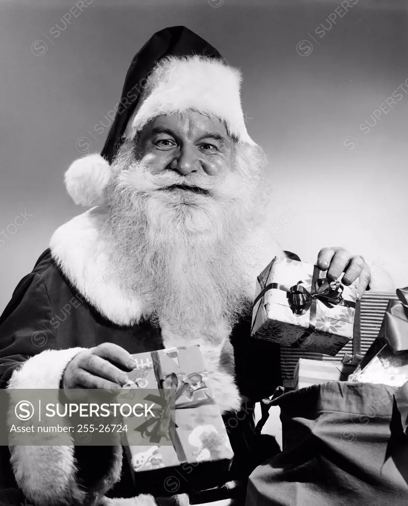 Portrait of Santa Claus holding Christmas presents and smiling