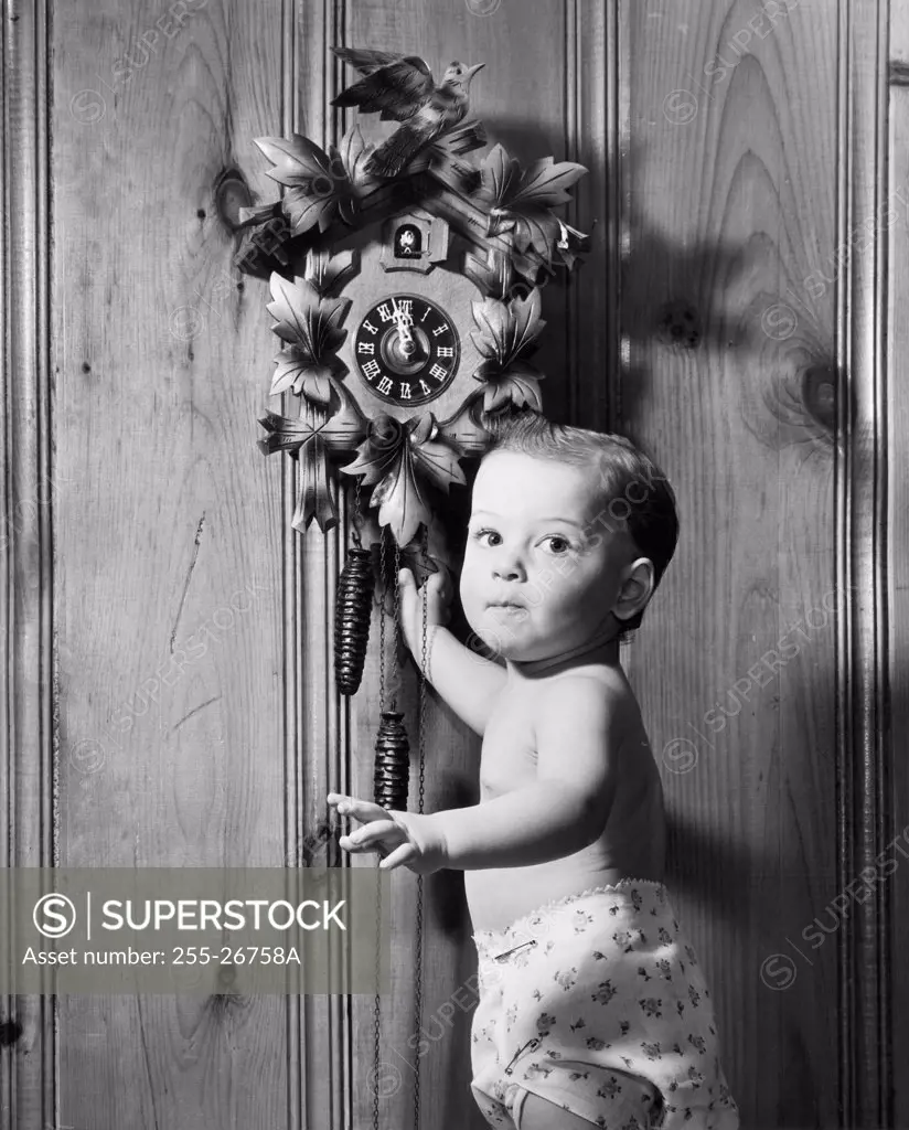 Portrait of a baby boy standing near a cuckoo clock