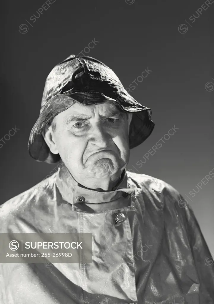 Vintage photograph. Man in rain hat and rain coat frowning