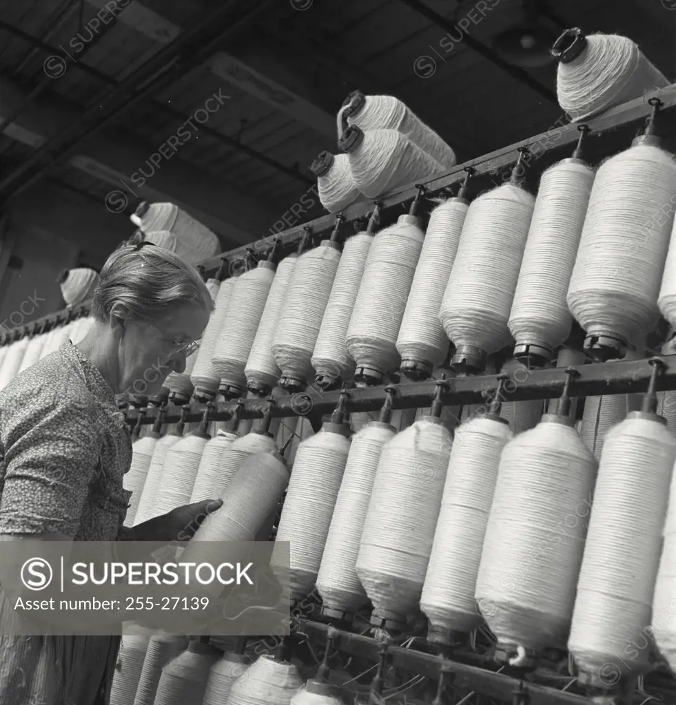 Vintage photograph. Side profile of a senior woman spinning cotton at cotton mill in Lousiana