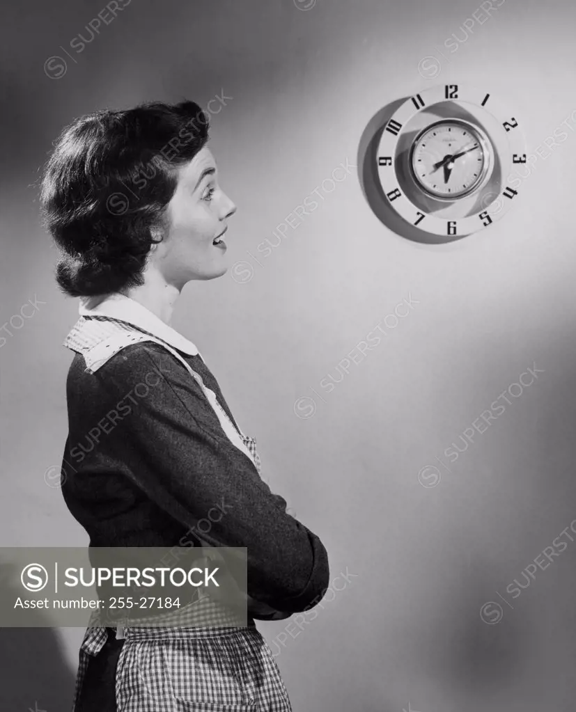Side profile of young woman looking at clock