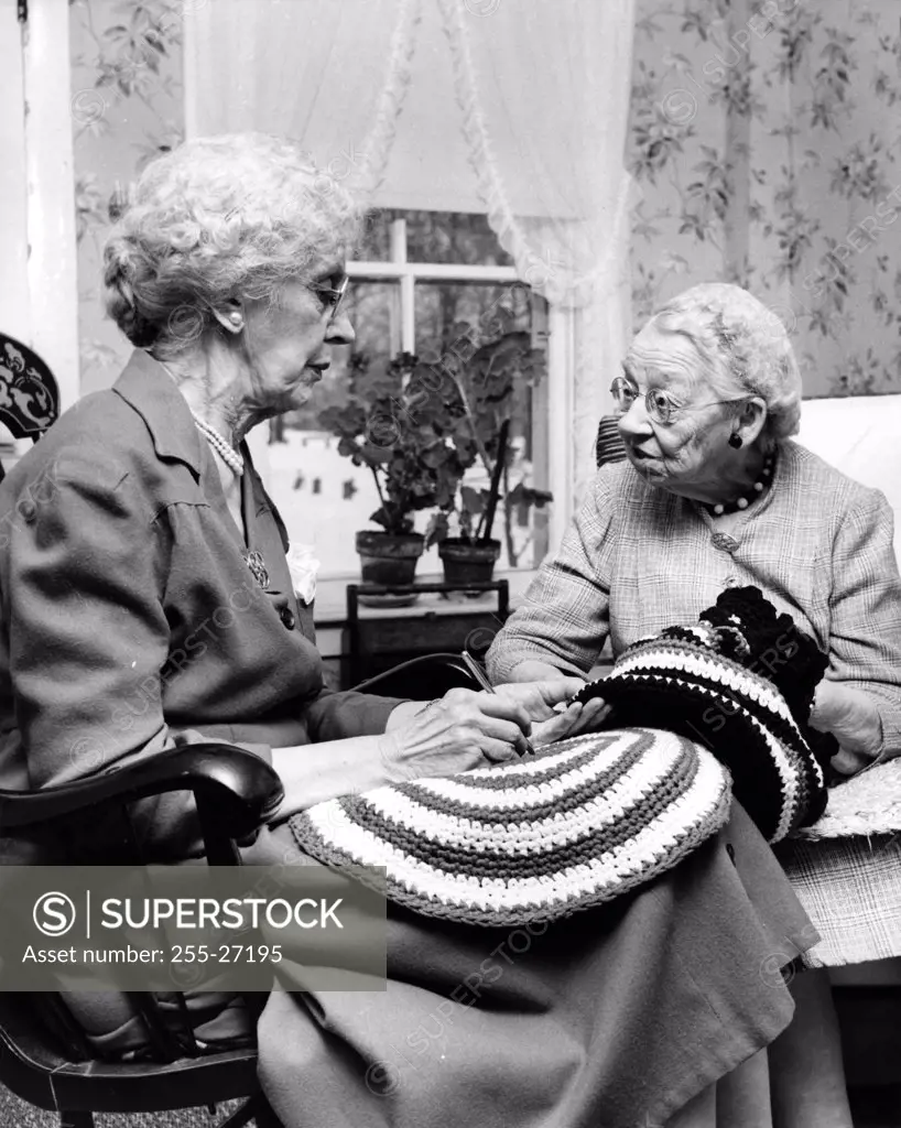 Pair of senior ladies talking while knitting