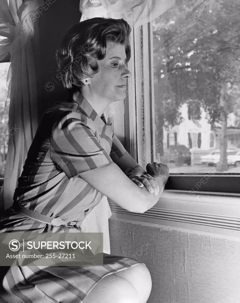 Side profile of a young woman looking through a window