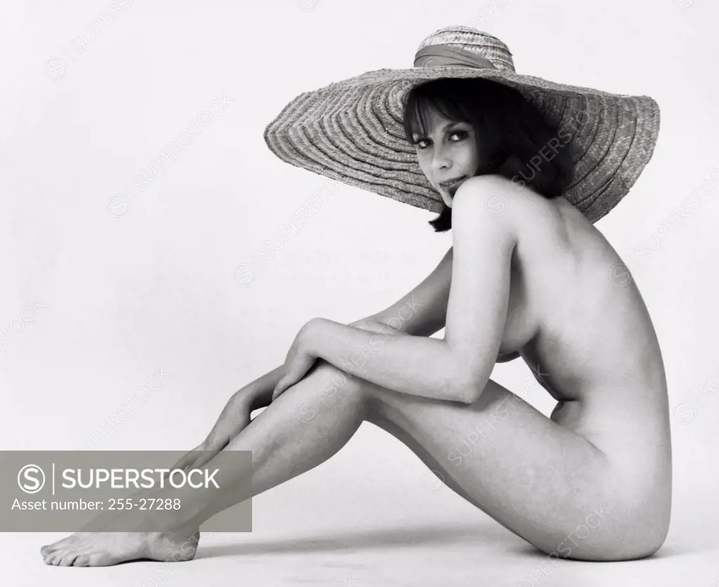 Portrait of a nude young woman wearing a sunhat