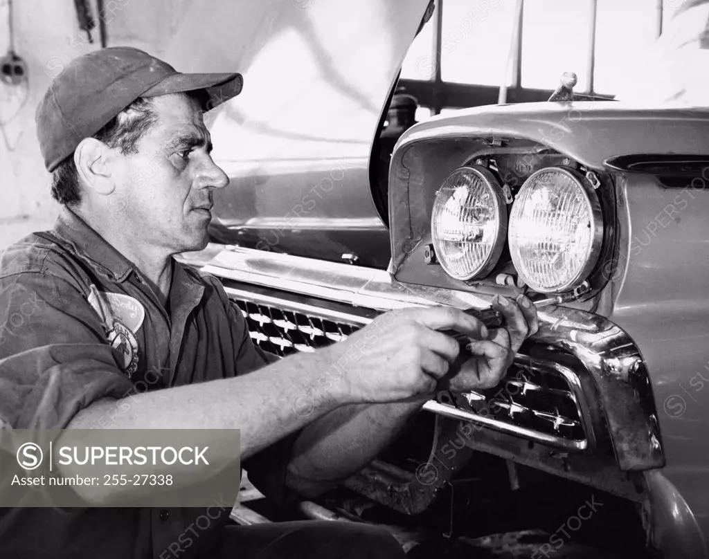 Close-up of a gas station attendant adjusting headlight of a car