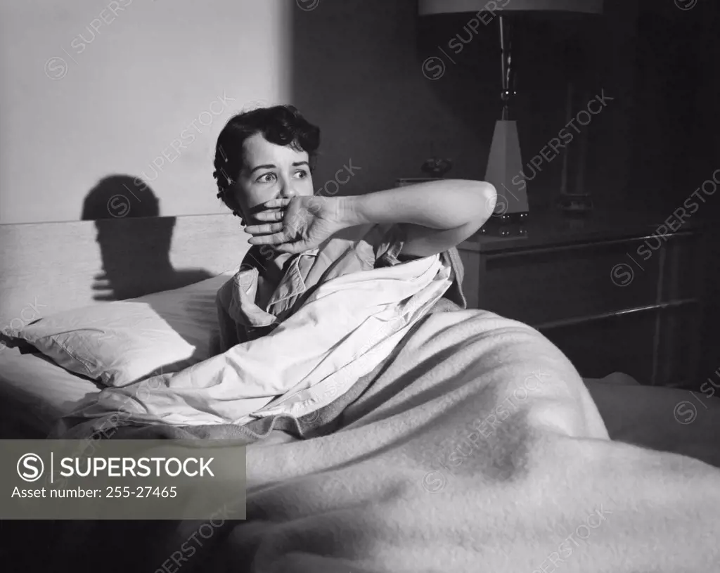 Young woman lying on the bed looking afraid