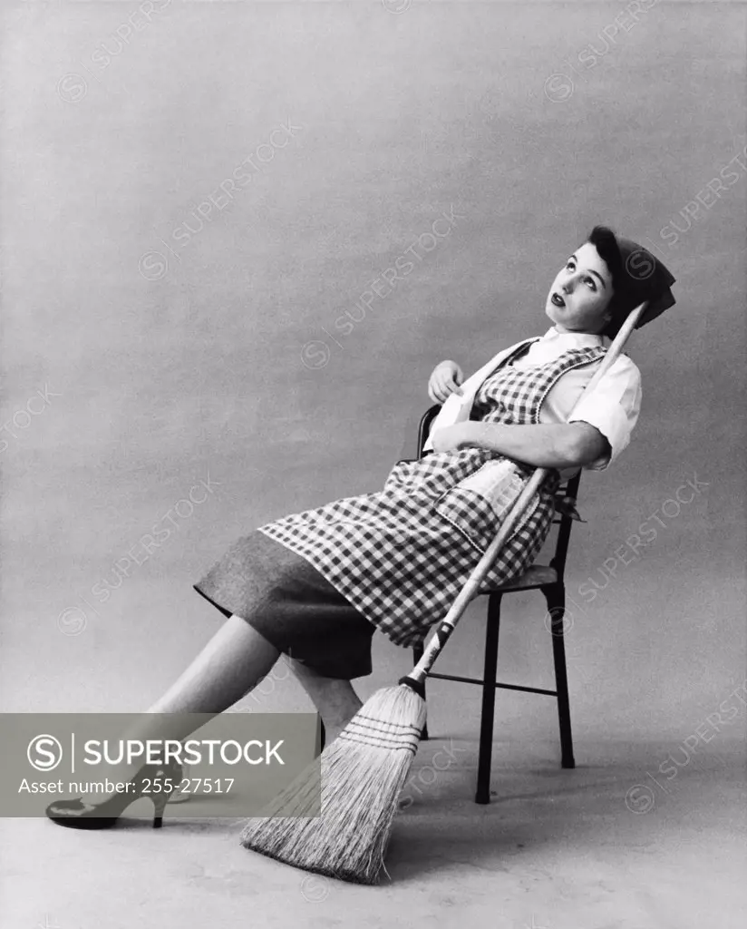 Young woman sitting on a chair holding a broom stick