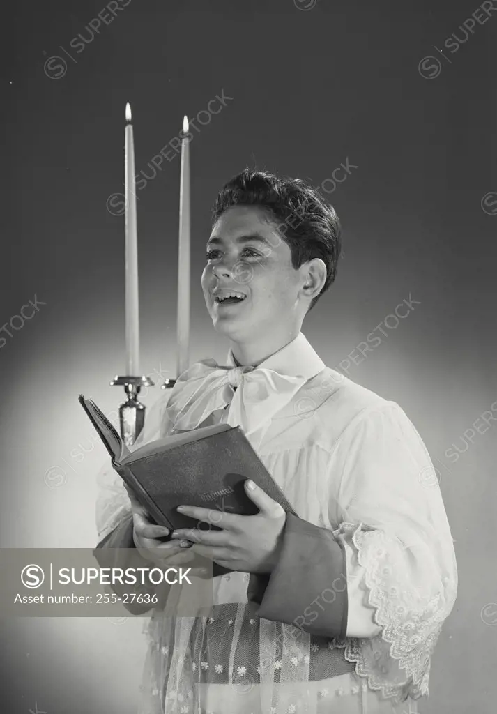 Altar boy holding hymnal book with candles in background