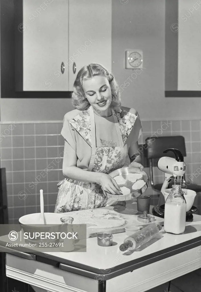 Vintage photograph. Young woman preparing cookies in the kitchen