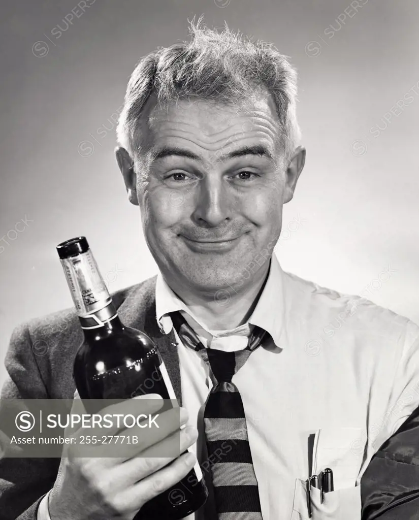 Close-up of a drunk senior man holding a alcohol bottle