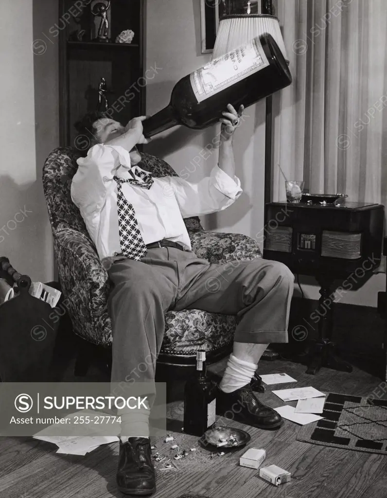 Young man drinking alcohol from a huge bottle