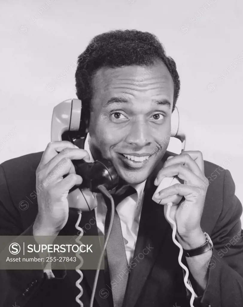 Close-up of a businessman using three telephones
