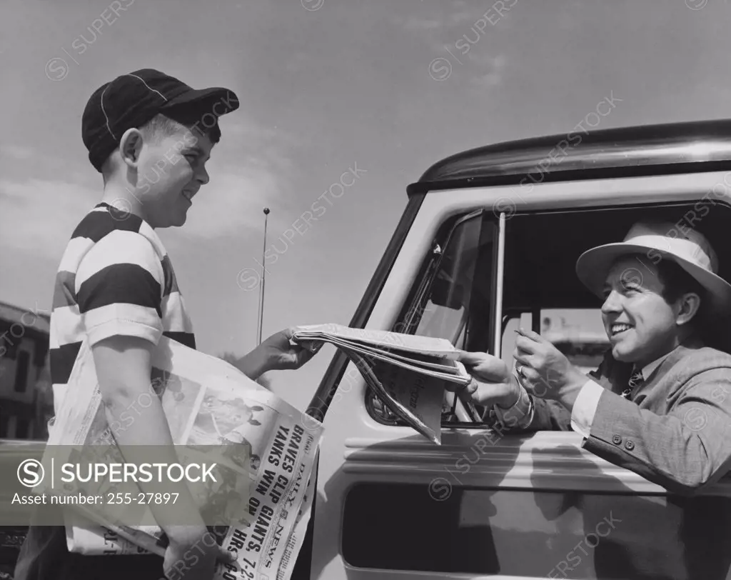 Young man buying a newspaper from a paper delivery boy