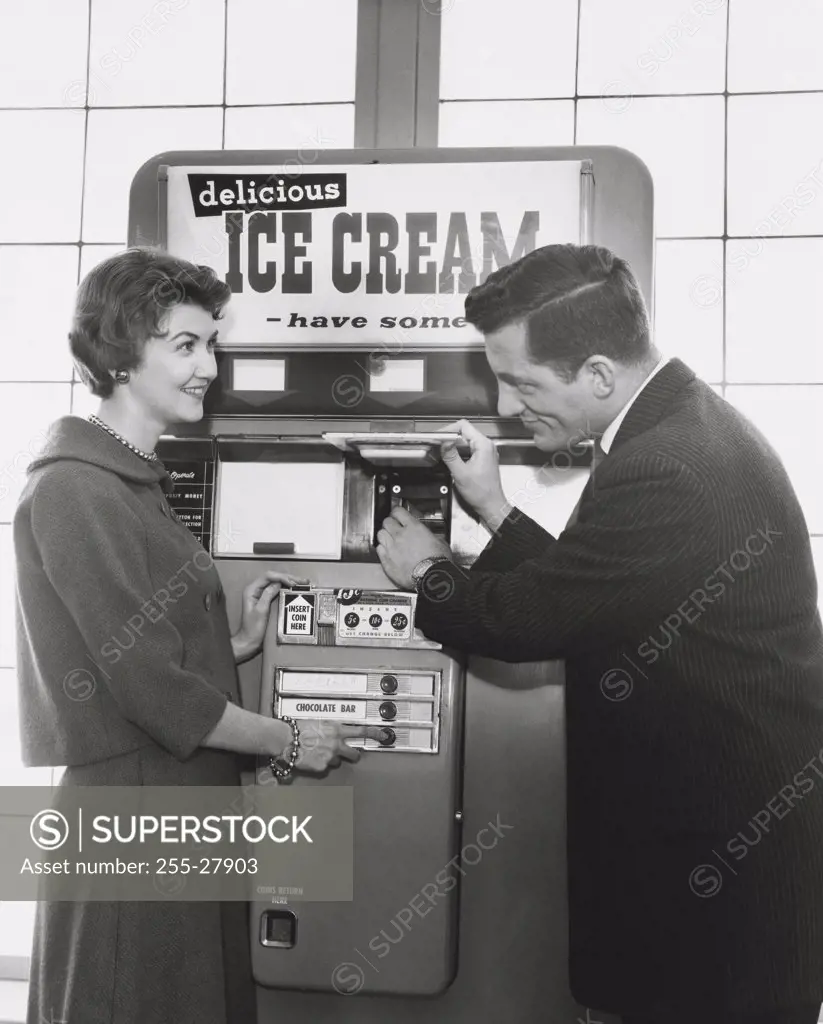 Mid adult couple purchasing ice cream from a vending machine