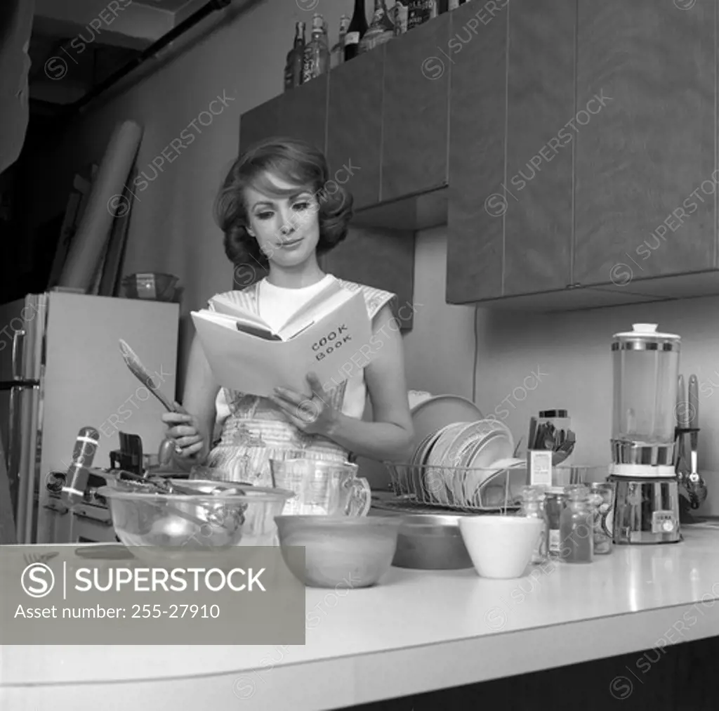 Woman reading cookbook in kitchen