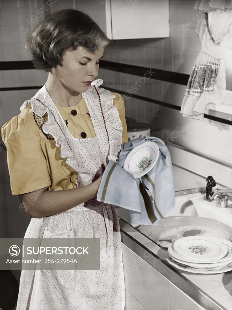 Young woman cleaning dishes in kitchen