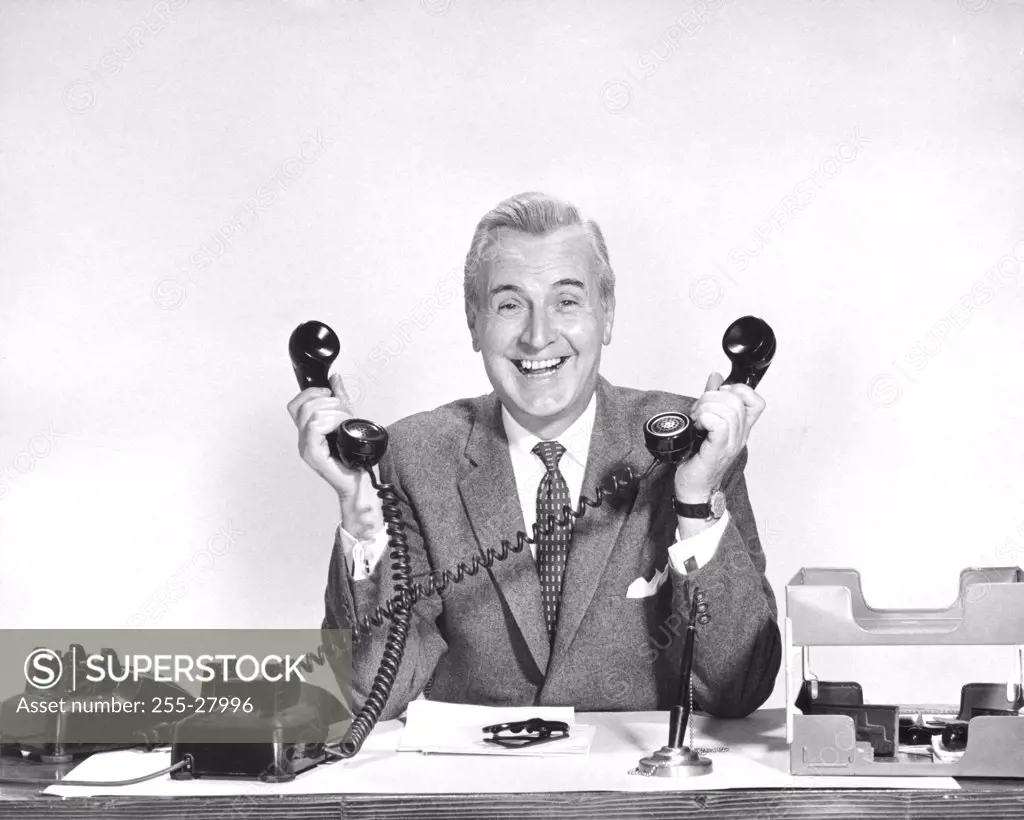 Portrait of a businessman holding two telephone receivers