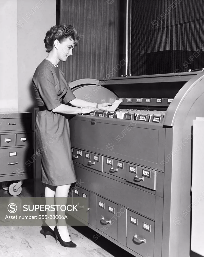 Businesswoman reading a document beside a filing cabinet