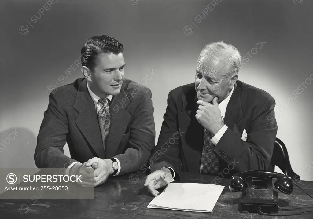 Young man and older man sitting together at desk