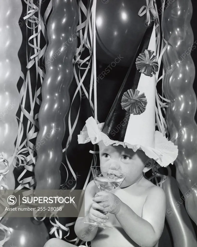 Close-up of a baby boy sipping champagne from a glass