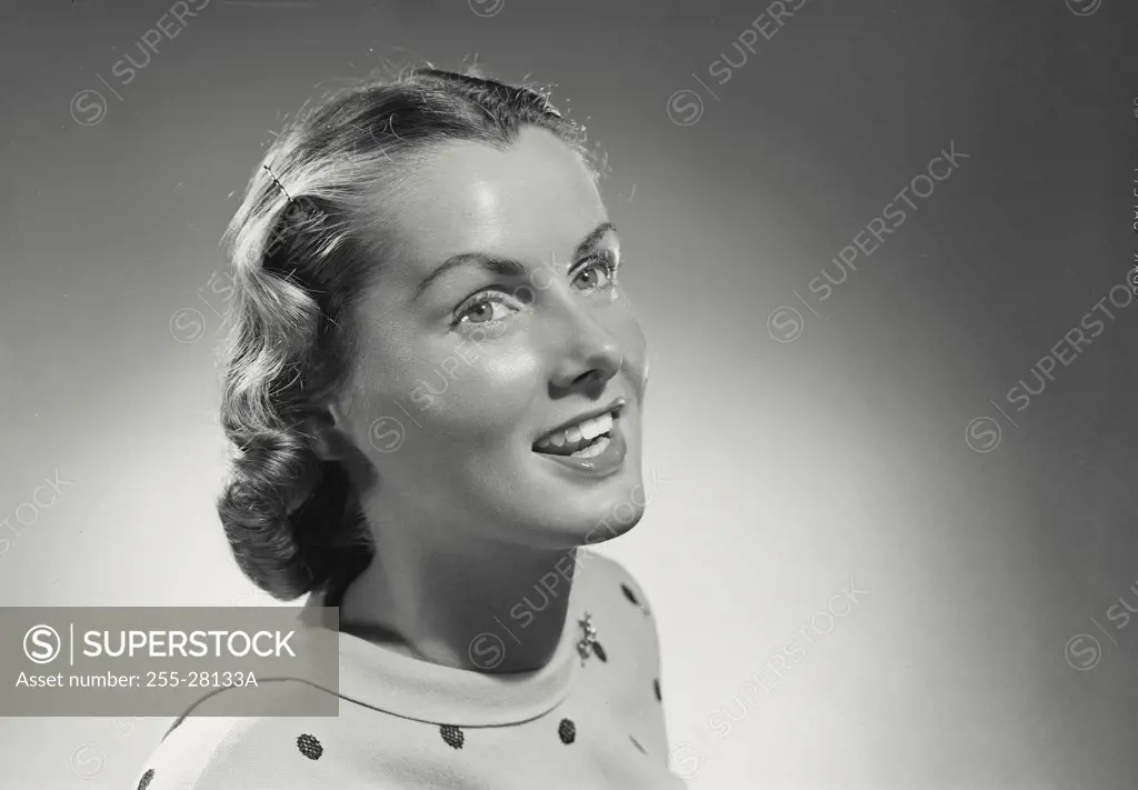 Vintage photograph. Woman with short hair in polka dot blouse smiling.