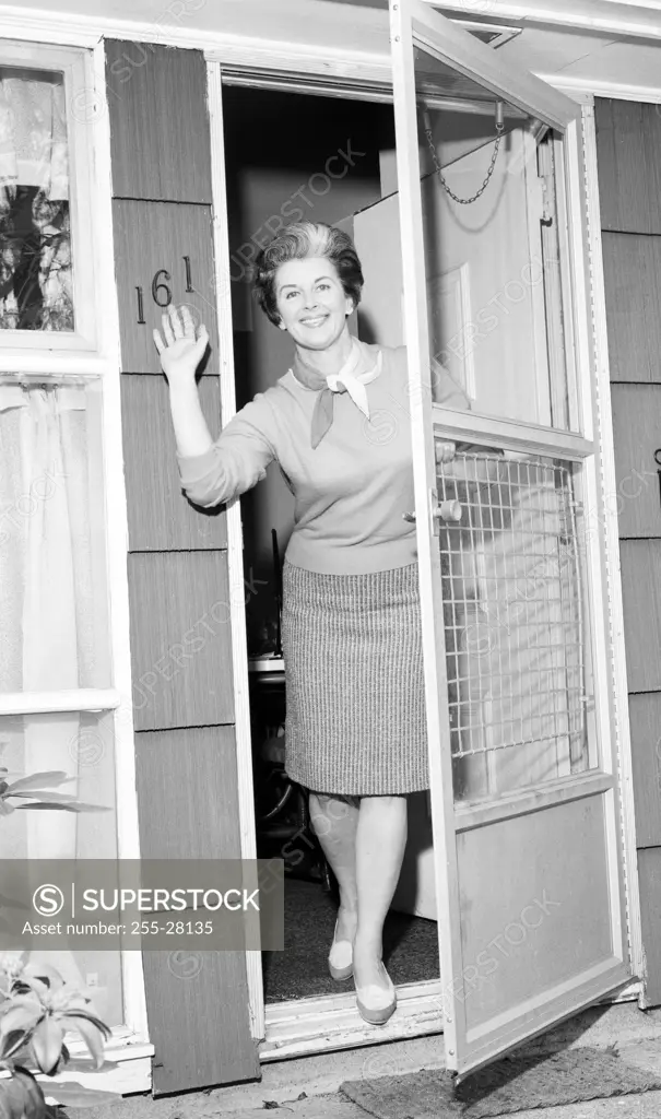 Woman in doorway waving to camera