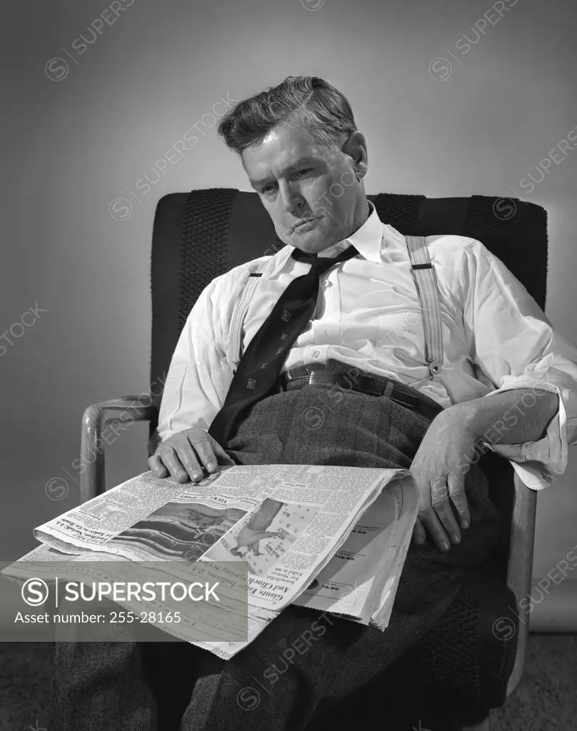 Mature man sitting on chair with newspaper
