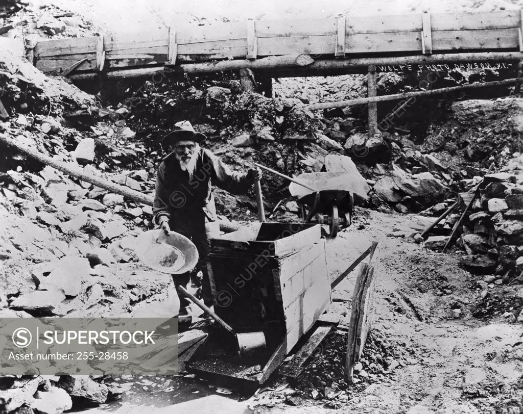 Miner panning for gold using gold rocker, Alaska, USA