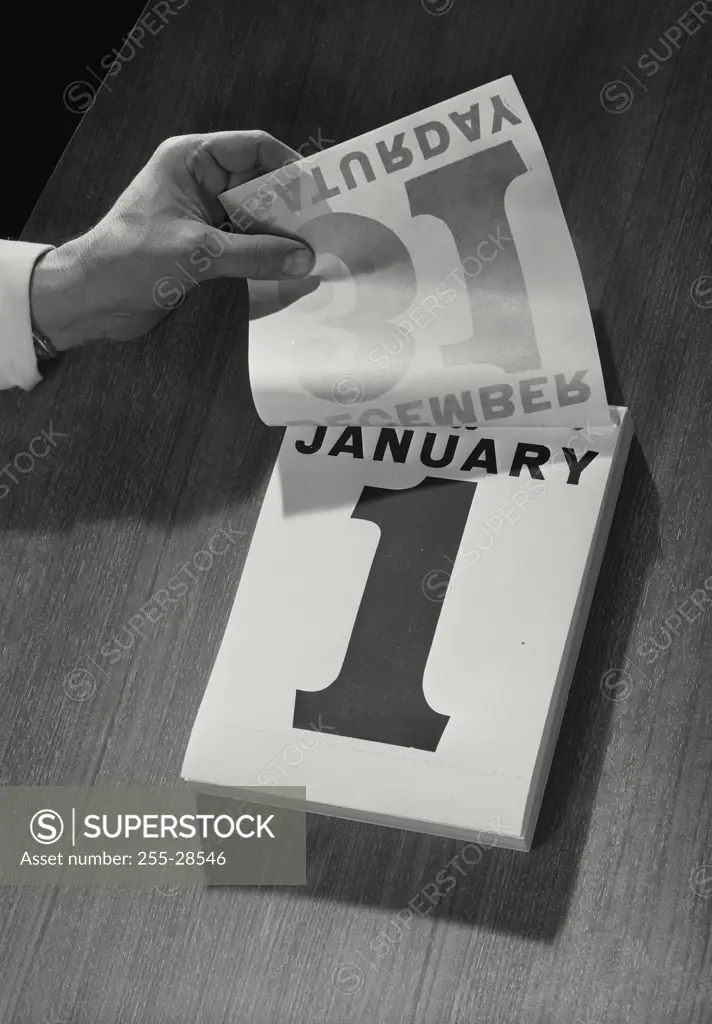 Vintage Photograph. Hand flipping up page of daily calendar from December 31st to January 1st, New Years Day, Frame 1