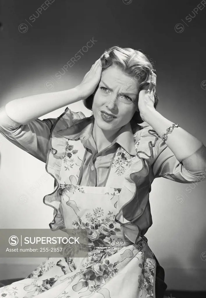 Vintage photograph. Woman in flower apron in pain with hands on head