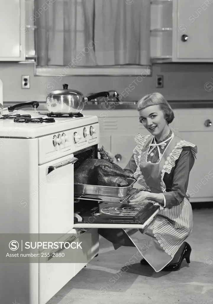 Vintage Photograph. Woman in apron basting turkey in oven. Frame 2