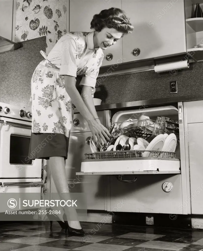 Low angle view of a young woman picking up a spoon from a dishwasher